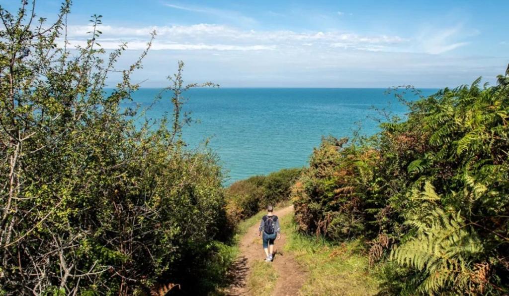 un homme marchant sur un chemin de terre près de l'océan dans l'établissement Camping 3 étoiles - ccbc0hb, à Pordic