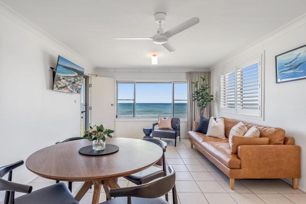 Absolute Beachfront Apartments 3T في لينوكس هيد: غرفة معيشة بها أريكة وطاولة