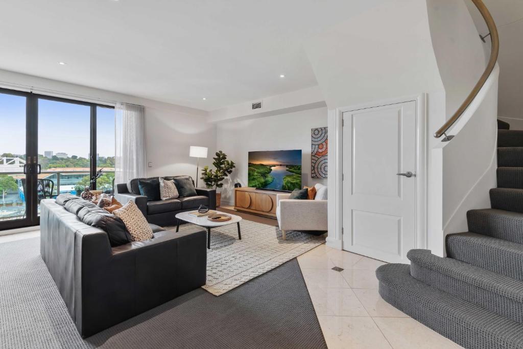 a living room with a couch and a staircase at Spacious 3-Bed Apartment by the MCG in Melbourne