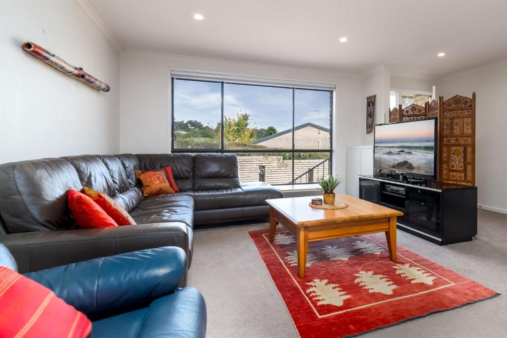 a living room with a leather couch and a television at Spacious and Restful Holiday Home with Backyard in Weetangerra