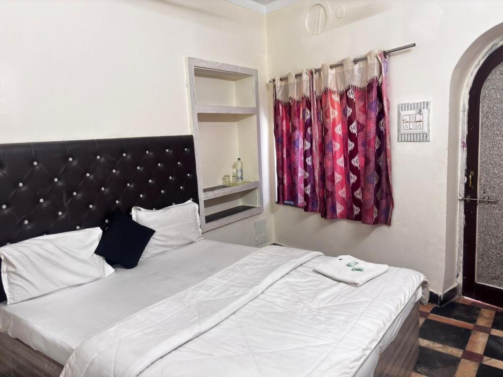 un dormitorio con una cama grande blanca con cabecero negro en Hotel SNR, en Mount Abu