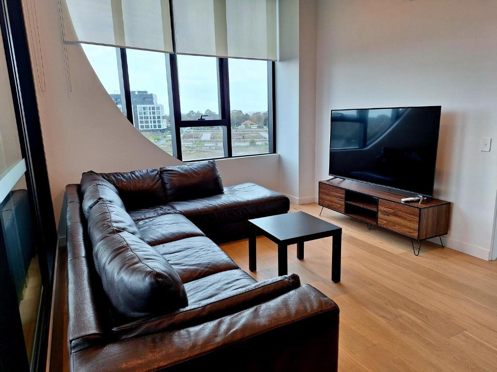 ein Wohnzimmer mit einem Ledersofa und einem Flachbild-TV in der Unterkunft Generous 2-Bed Apartment with Great Amenities in Melbourne