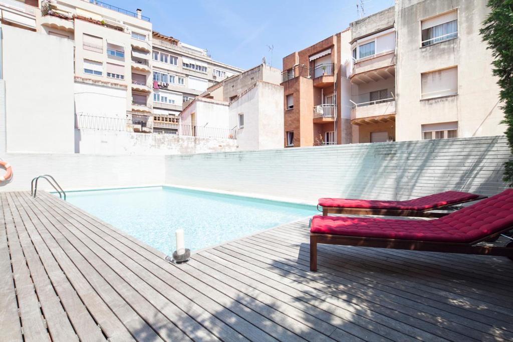 バルセロナにあるApartment Barcelona Rentals - Swimming Pool with Terraceの建物の隣に長椅子付きのスイミングプール