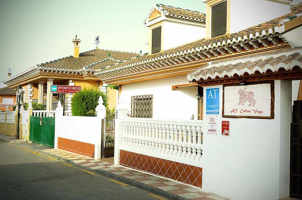 ein weißes Gebäude mit einem Schild an der Straßenseite in der Unterkunft Apartamentos Turísticos Cúllar Vega in Cúllar-Vega