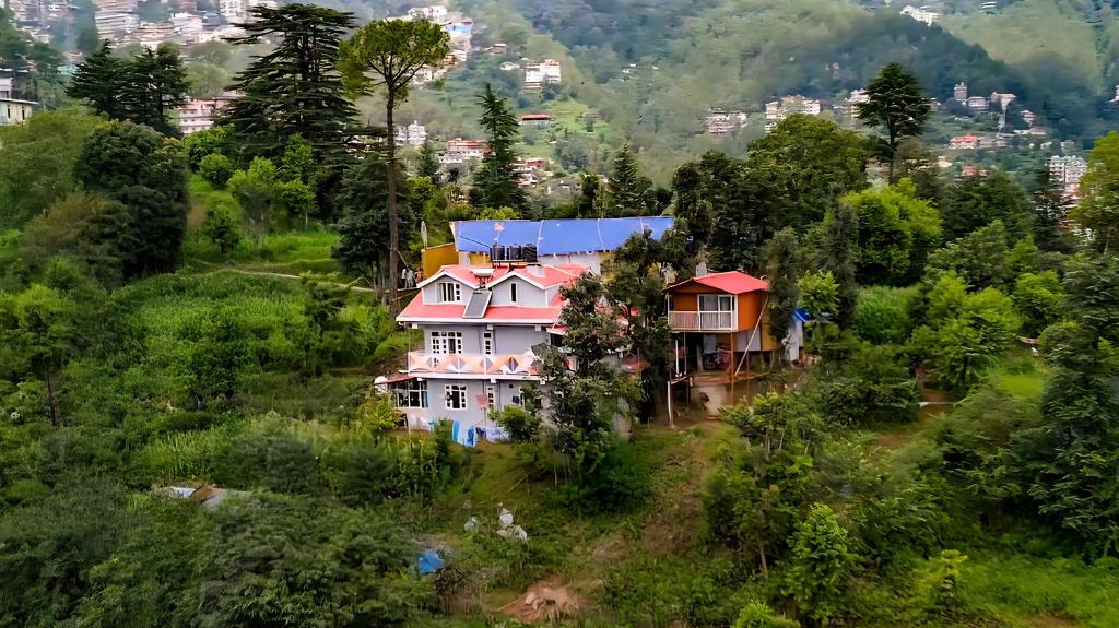 une maison sur une colline avec une ville en arrière-plan dans l'établissement The City Escape Farmstay, à Shimla
