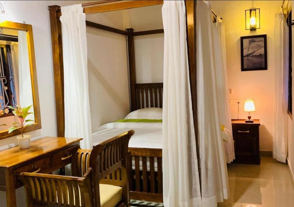 ein Schlafzimmer mit einem Himmelbett, einem Schreibtisch und einem Schreibtisch in der Unterkunft The Boho Cochin in Kochi