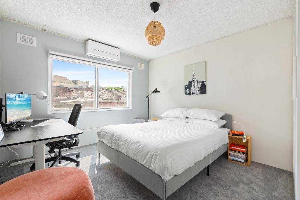 Un dormitorio con una cama y un escritorio con una computadora. en Cosy Sydenham 1-Bed by Inner-West's Attractions, en Sídney