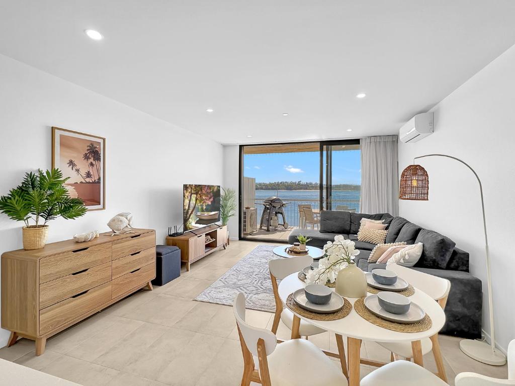 uma sala de estar com um sofá e uma mesa em Modern 1-Bedroom Apt with Sweeping Water Views em Batemans Bay