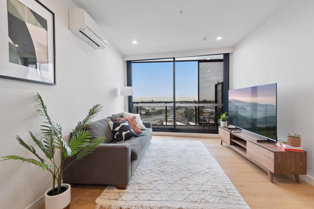 Una sala de estar con un sofá y una ventana grande. en Contemporary 2-Bed Haven with Swimming Pool, en Clayton North