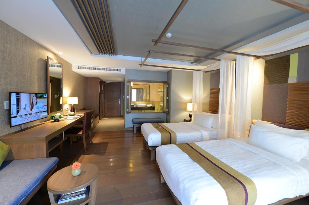 A twin room with two beds, a television, desk, and a visible vanity area.