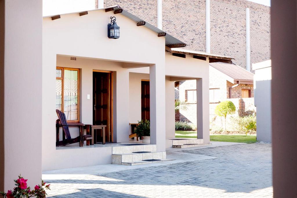 a white house with a porch with a chair at Welgerust Bed & Breakfast in Piet Retief