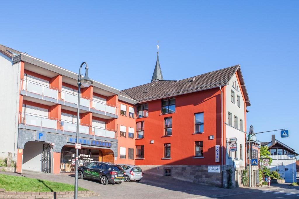 un bâtiment rouge avec des voitures garées devant lui dans l'établissement Frühstückshotel Landgasthof Kramer, à Eichenzell