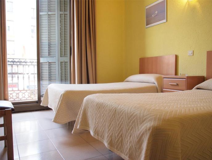 バルセロナにあるオスタル デルフォスのベッド2台と窓が備わるホテルルームです。