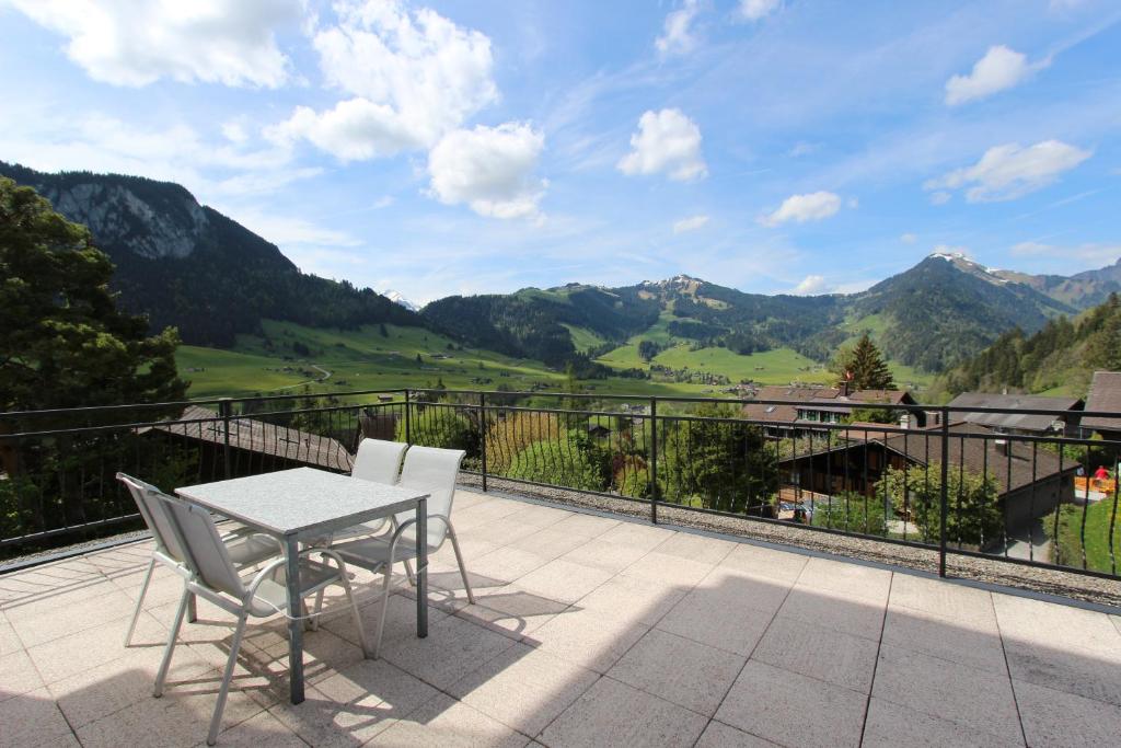 d'un balcon avec une table, des chaises et des montagnes. dans l'établissement Rosat 4, à Château-d'Oex