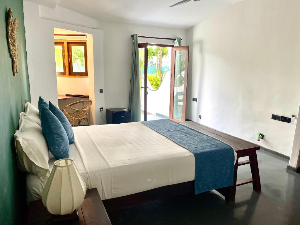 une chambre avec un grand lit blanc avec des oreillers bleus dans l'établissement Casa Smeralda, à Batigama