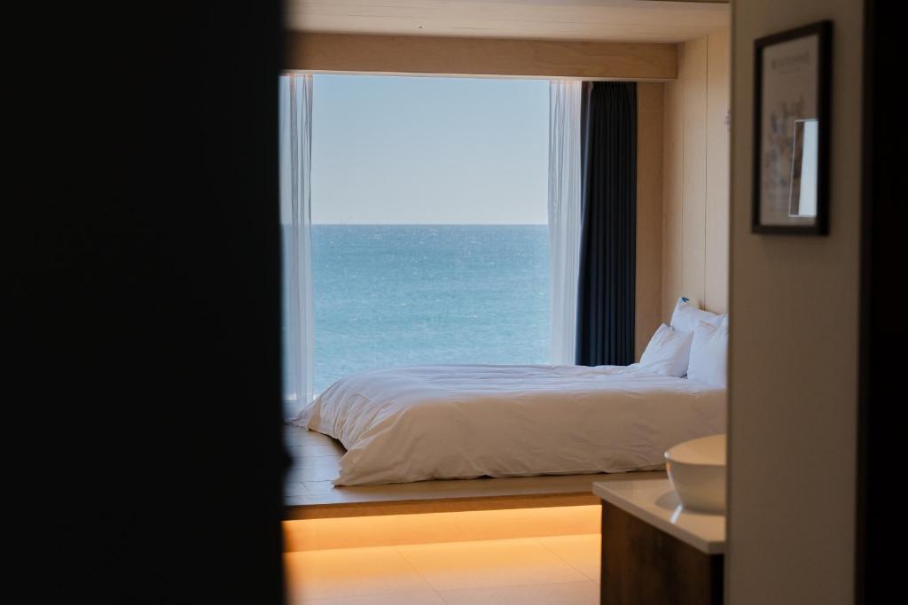 a bedroom with a bed and a view of the ocean at Hygge Hotel in Seogwipo