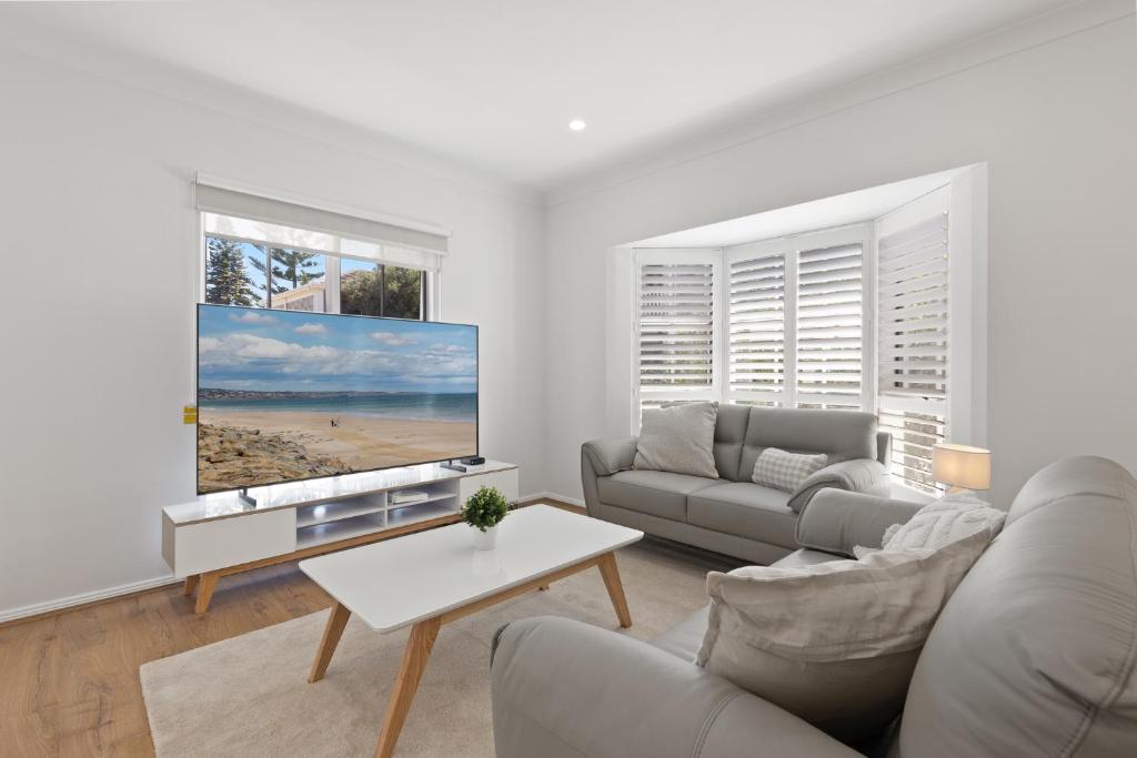 ein Wohnzimmer mit Couch und Flachbildfernseher in der Unterkunft Quiet 2-Bed Retreat with Private Courtyard in Glenelg