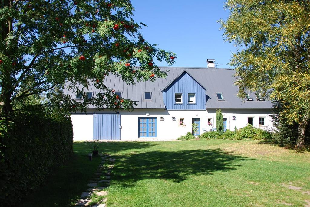 a white barn with a blue roof and a yard at Apartment Ptačí Dům in Sněžnik