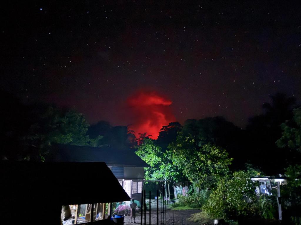 um incêndio em uma casa à noite com uma nuvem vermelha em Tanna fireworks homestay em Loméméti