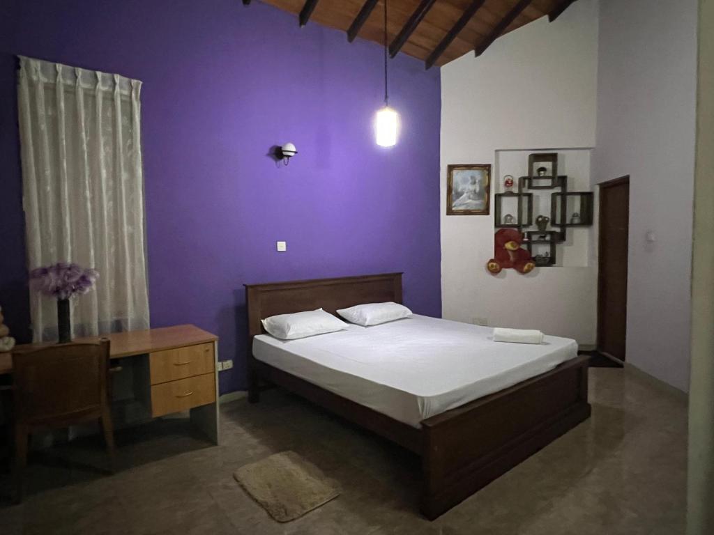 キャンディにあるSky rise mount hotelの紫の壁のベッドルーム1室(ベッド1台付)