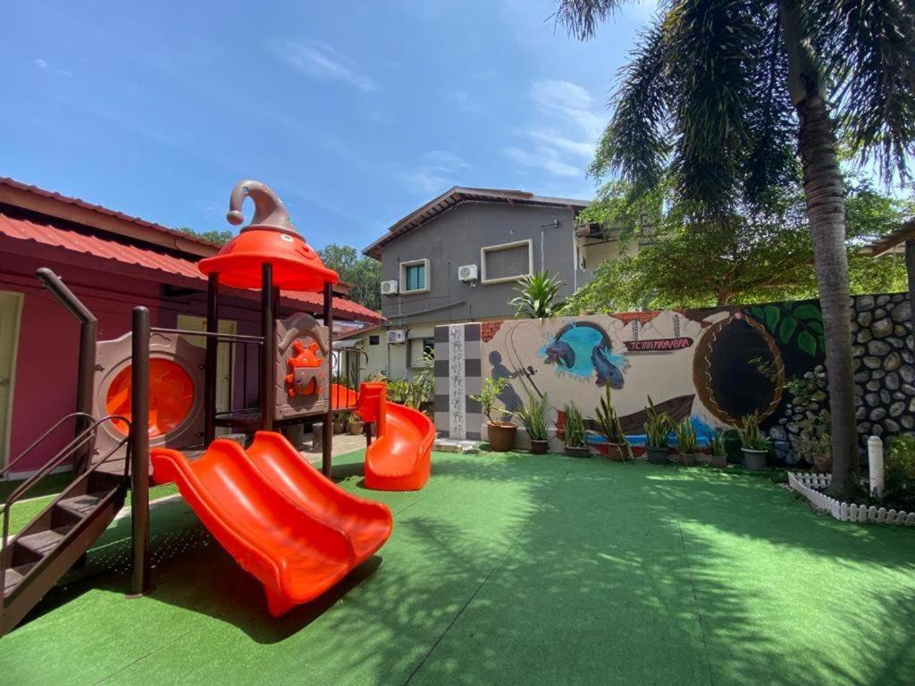 um quintal com um parque infantil com um escorrega em Family Budget em Kampong Telok Sisek
