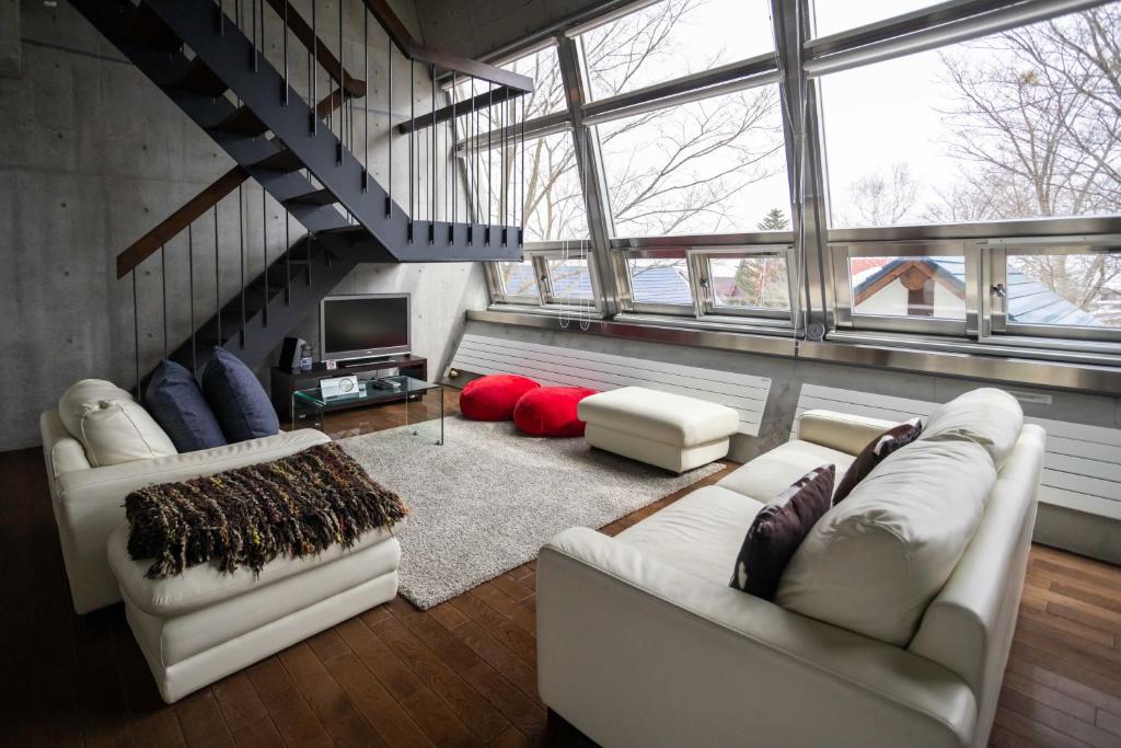 a living room with two white couches and a tv at Full Circle Apartments in Kutchan