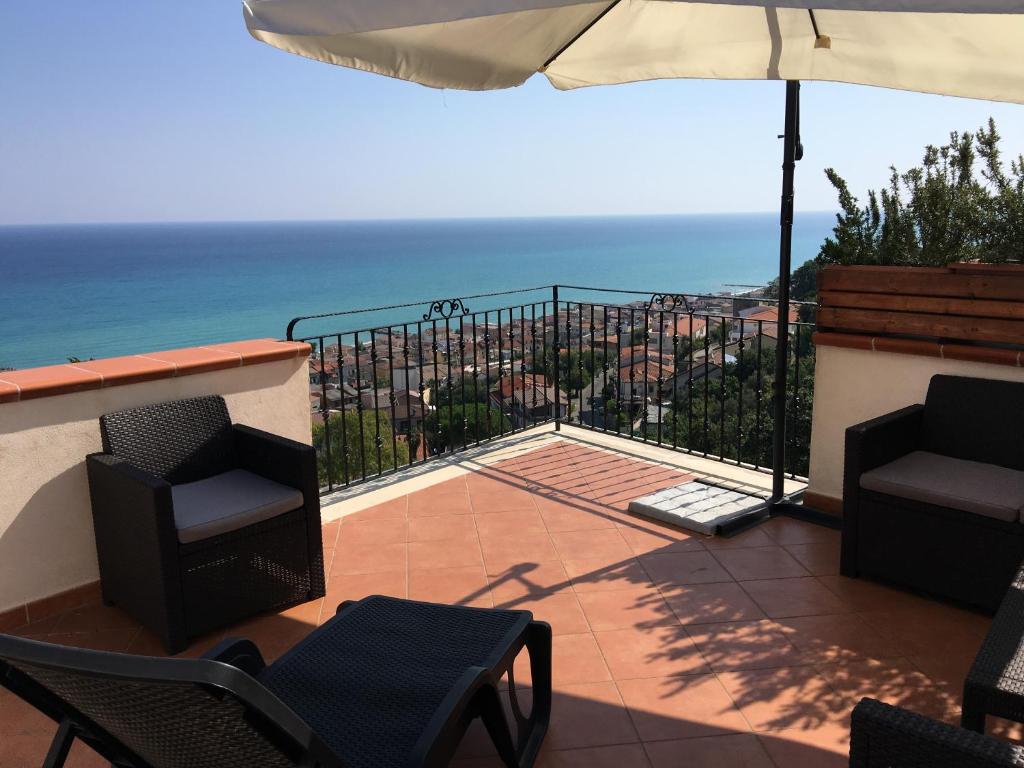 une terrasse avec des chaises et un parasol et l'océan dans l'établissement San Pio Bed & Breakfast, à Cariati