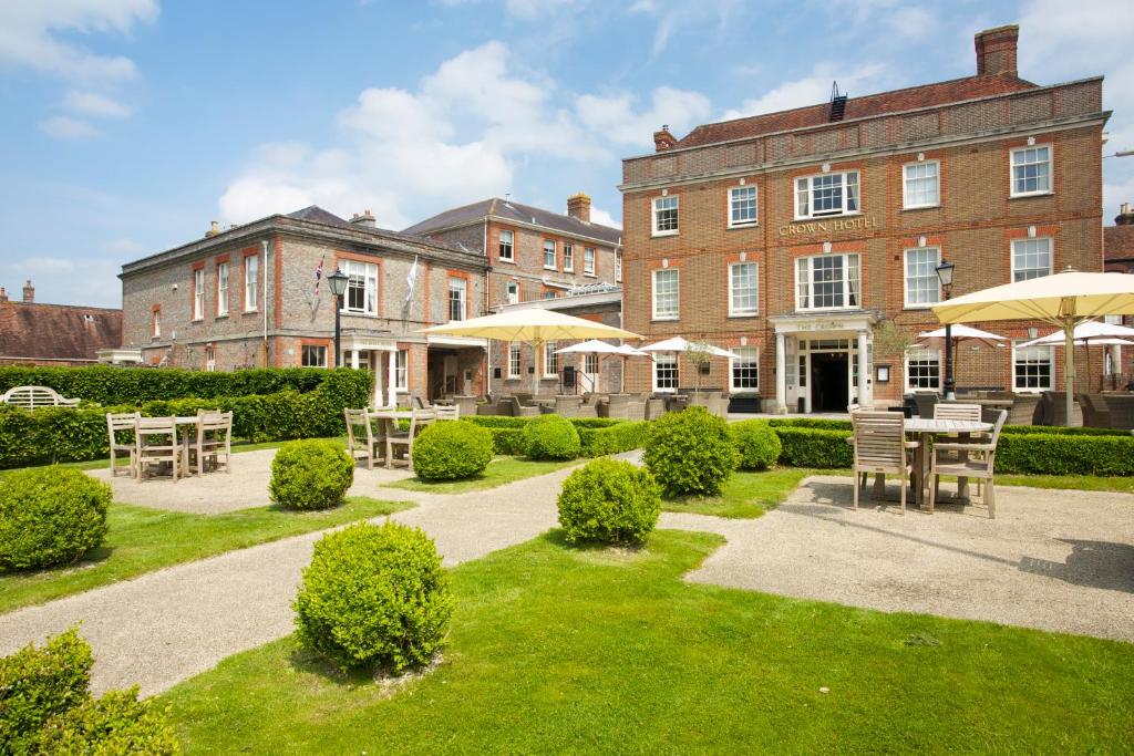 a building with tables and umbrellas in front of it at The Crown Hotel in Blandford Forum