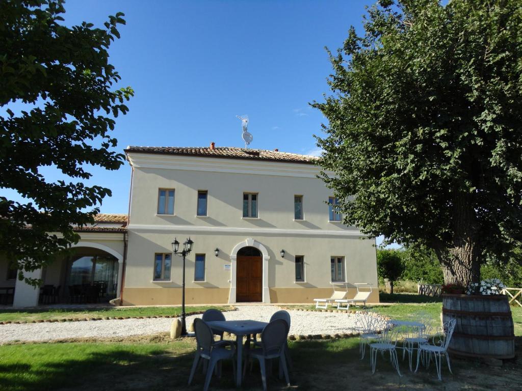 un edificio con una mesa y sillas delante de él en Villa Marietta Country House - Marche en Montemaggiore al Metauro