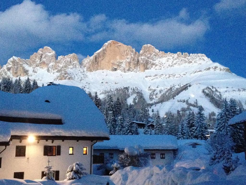 een gebouw met sneeuw bedekte bergen op de achtergrond bij Casa al Lago di Carezza - Dolomiti in Carezza al Lago