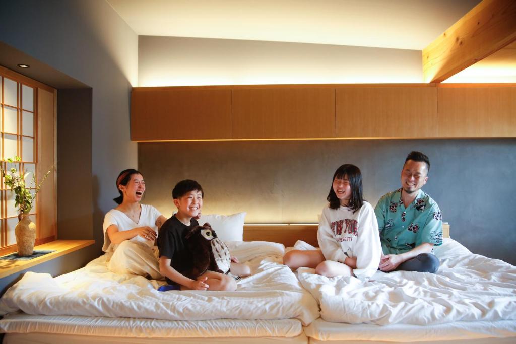 a group of people sitting on a bed at Temari Inn Madoromi in Kurashiki