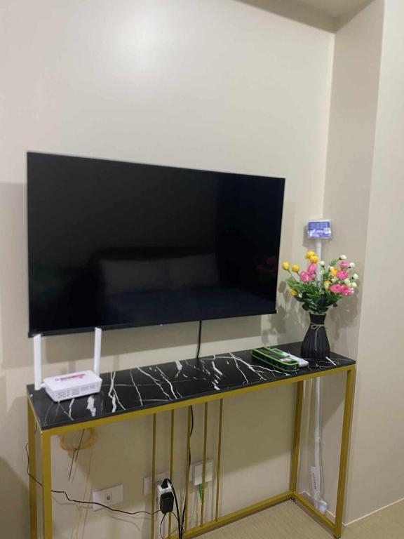a television on a table with a vase of flowers at CDO City Center Avida Condo Fast Wifi in Cagayan de Oro