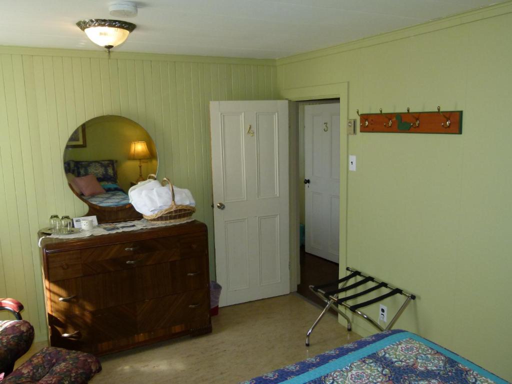 a bedroom with a mirror and a dresser and a bed at La Maison entre Mer Montagnes in Cap-Chat