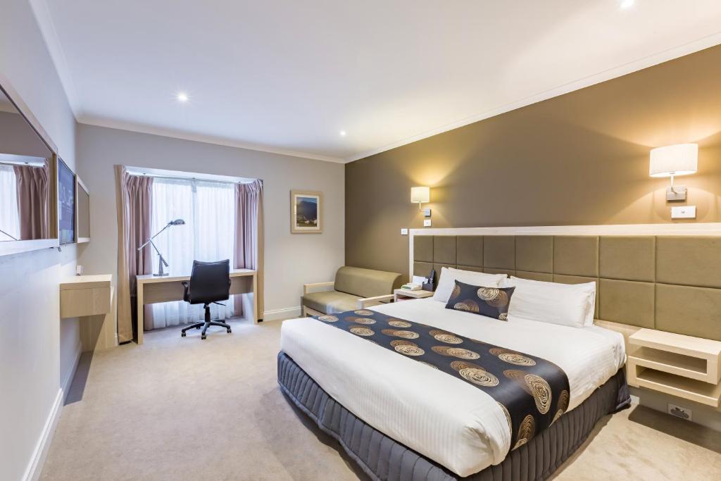 a hotel room with a bed and a desk at The Waverley International Hotel in Glen Waverley