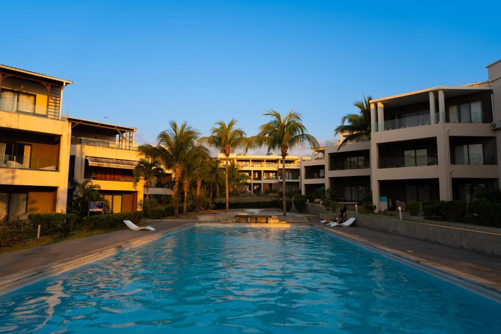 a swimming pool in front of a building with palm trees at Cozy Oceanview Apartment D5 in Flic-en-Flac