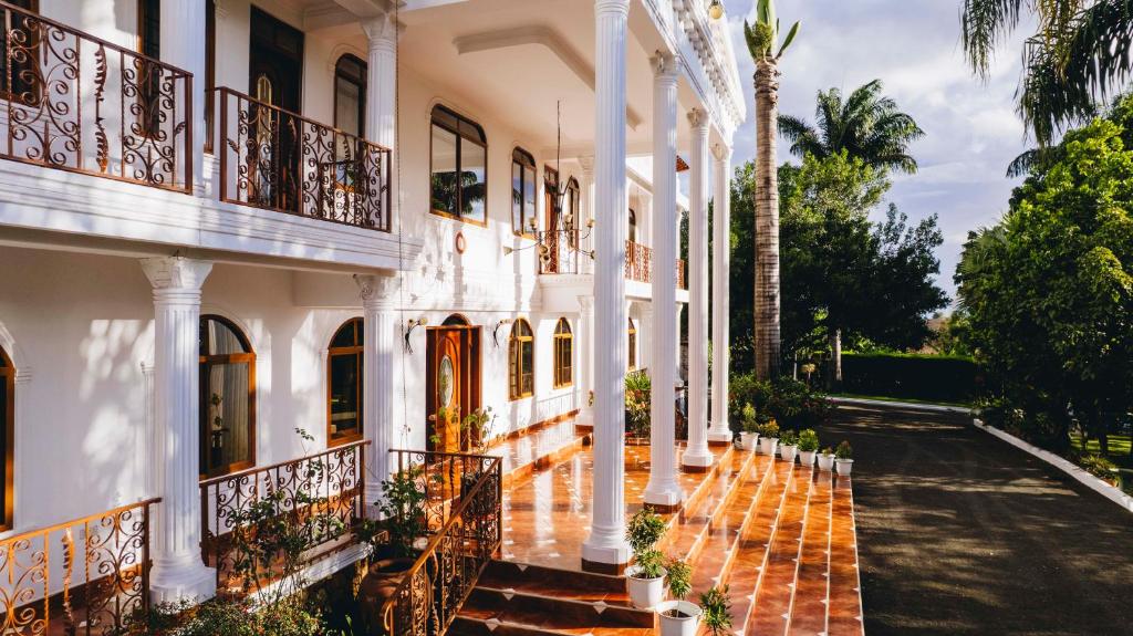 eine Außenansicht eines weißen Gebäudes mit Balkonen in der Unterkunft Naibor Villa in Themi