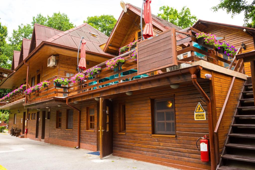 a wooden building with a balcony with flowers on it at Pensiunea Casa Verde Bucuresti in Bucharest