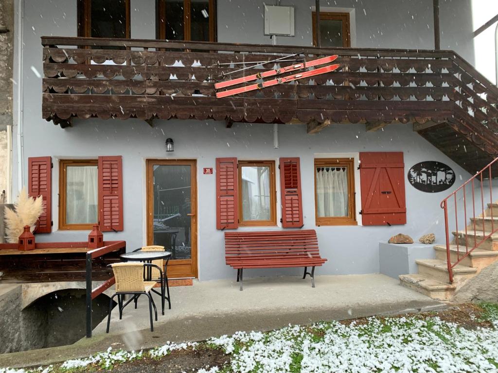 ein Haus mit roten Fensterläden, einer Bank und einem Tisch in der Unterkunft Les cols in Sainte-Marie-de-Cuines