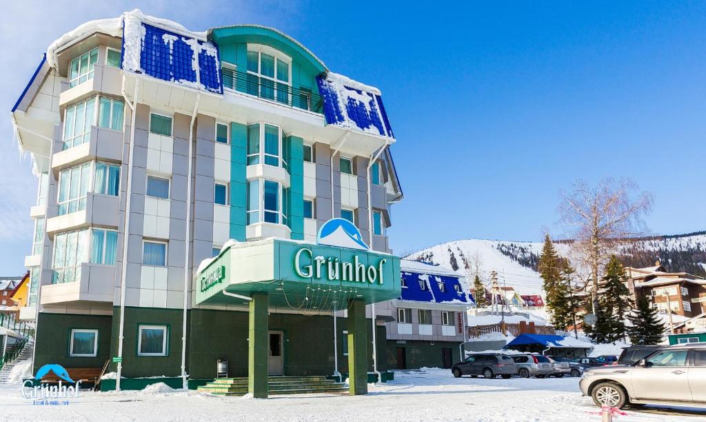 a building with a sign in front of it in the snow at Grünhof in Sheregesh