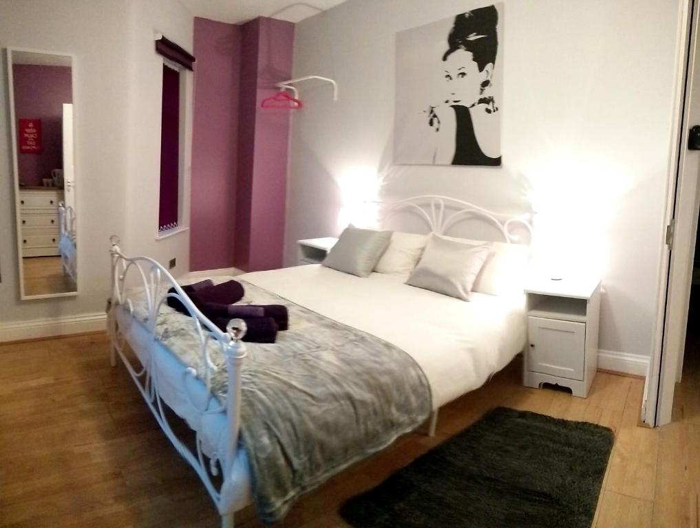 Un dormitorio con una cama blanca y una pintura en la pared en Old Trafford Guest House, en Mánchester