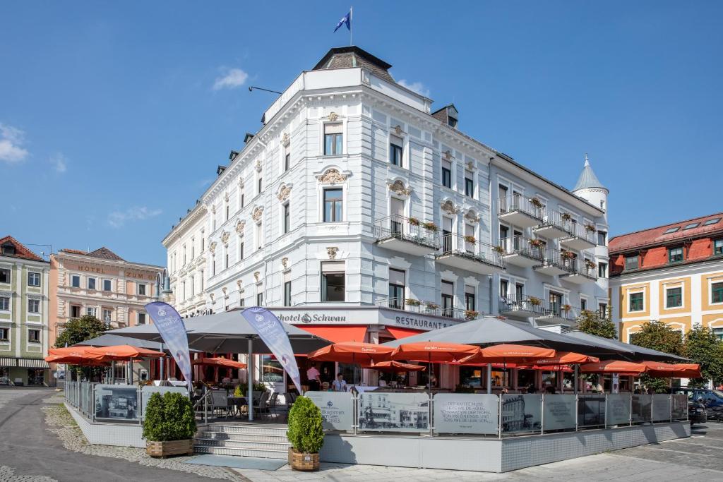 a building with tables and umbrellas in front of it at Seehotel Schwan in Gmunden