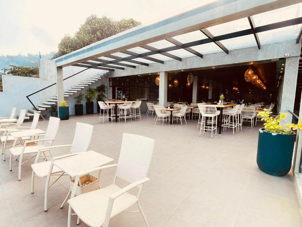 un patio avec des chaises blanches, des tables et des chaises dans l'établissement Casa Escondida Anilao Resort And Dive Center, à Mabini