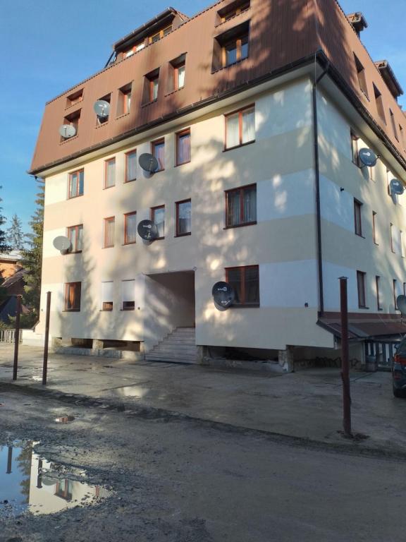 a large white building with a brown roof at Apartman Vlašićki san in Vlasic