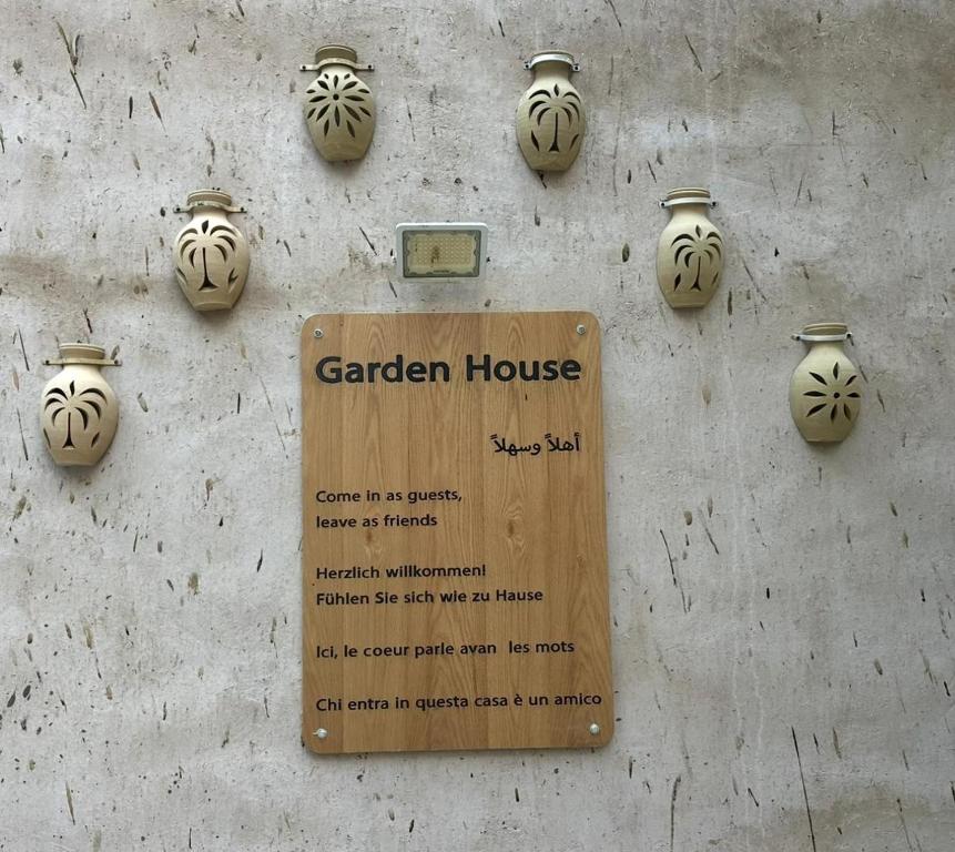 a sign on a wall with vases on it at Garden House in Al Ḩamrāʼ