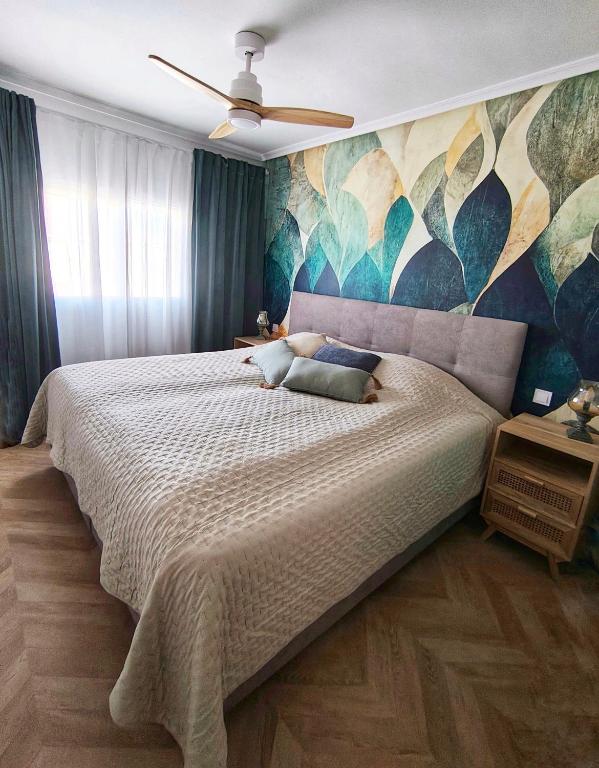 a bedroom with a large bed with a painting on the wall at Light Blue Apartment Orihuela Costa in Orihuela Costa