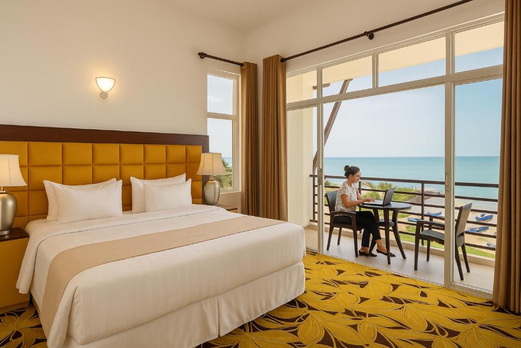 una habitación de hotel con una cama y una mujer sentada en una mesa en Beverly Beach Hotel & Transit, en Negombo