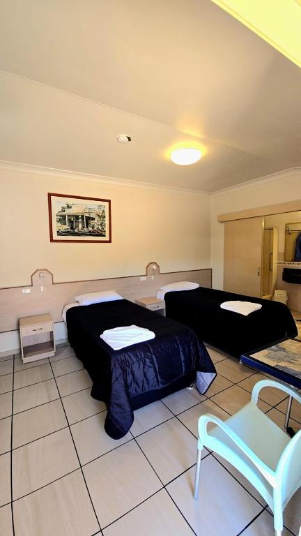 a room with two beds and a chair in it at Royal Motel Rockhampton in Rockhampton