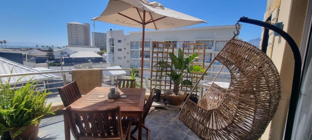 ein Balkon mit Tisch und Stühlen und einem Sonnenschirm in der Unterkunft Ocean Escape Apartment in Strand