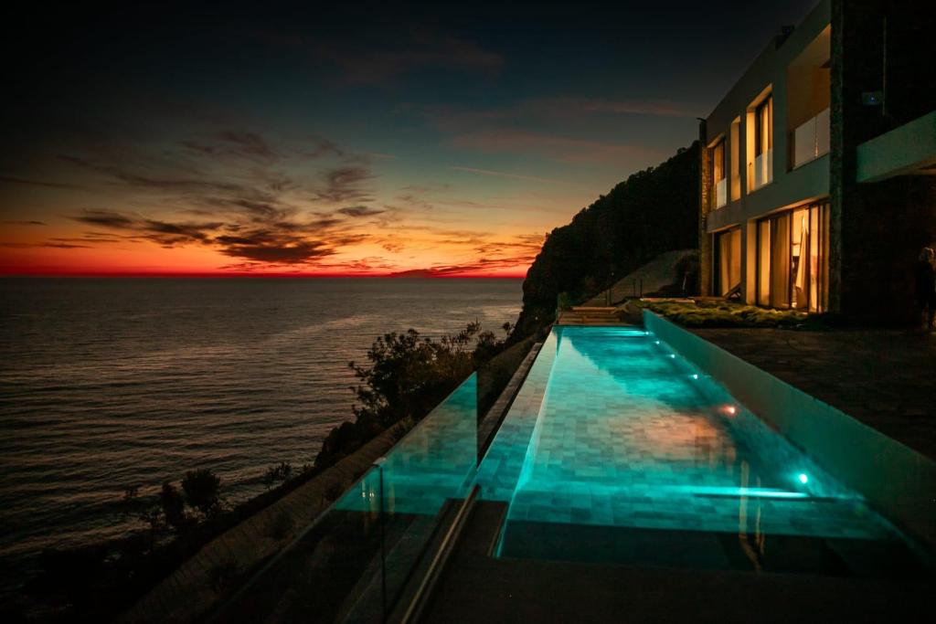 een gebouw met een zwembad naast de oceaan bij The Cliff Residences in Melínta