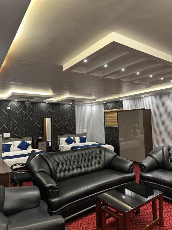 a living room with a leather couch and two beds at Thottunkal Tourist home in Kadavoor